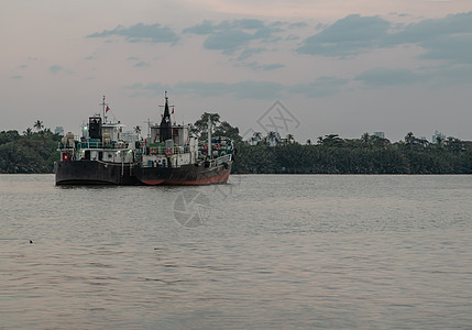 晚上停在Chao Phraya河中部的两艘货轮 其背景为绿林和天空图片