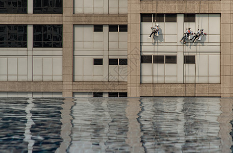 一群工人在高楼办公大楼打扫窗户服务 并配有反射纤维泳池安全财产风险工作危险团体绳索场景高度设施图片