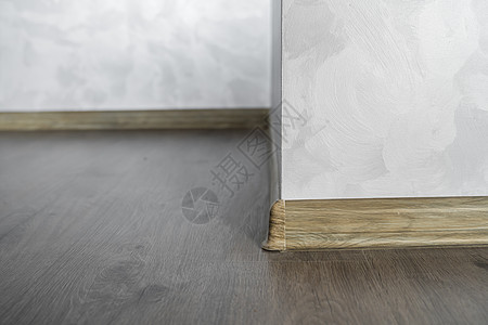与具有木质纹理的塑料底板层压 家里新安装的强化木地板和踢脚板 现代设计 深色橡木地板镶木地板上塑料底座的特写房子建筑学地面建筑装图片