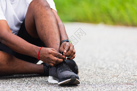 坐在鞋带上尝试跑鞋的黑人男子活动赛跑者体育场运动员黑色跑步运动训练衬衫慢跑者图片