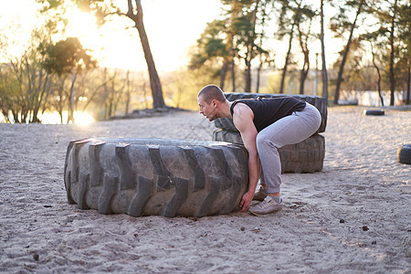 强力男子训练锻炼运动 在户外DY健身房举起大轮胎专注身体男性车轮重量活动活力肌肉二头肌运动员图片