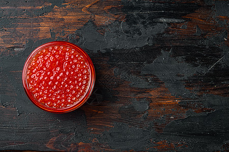 玻璃杯罐 有美味的红鱼子酱 在旧黑木木桌背景上 顶层视图平板 复制文字空间背景图片
