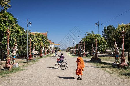 佛教寺庙在柬埔寨干丹省塔田外行走的佛教和尚街道高棉语橙色佛教徒生活花园小和尚宗教遗产宝塔背景