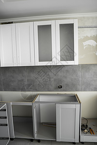 带有白色家具外墙 mdf 的定制厨柜安装 灰色模块化厨房由刨花板材料制成 处于不同的安装阶段 框架家具正面是 mdf 型材房子工图片