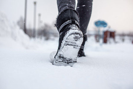 一个人在滑滑的路上行走 在公园里第一次下雪冻结天气皮革鞋类运动远足雪花活动衣服季节图片