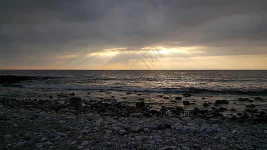 阴云的日落戏剧性海景多云海洋地平线海滩天气石头太阳阳光图片