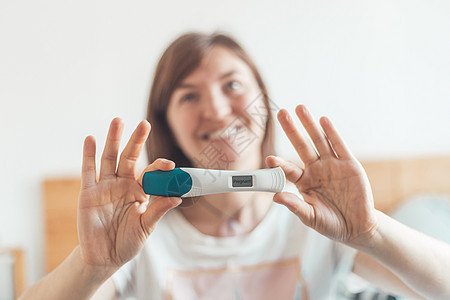 幸福的妇女在床上坐着 检查怀孕测试 结果呈阳性 孕妇生育力卫生保健医学快乐女性排卵婴儿夫妻生活图片