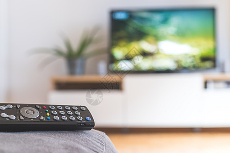 在沙发上的遥控器 流到智能电视上娱乐技术渠道家庭房间展示影院监视器程序控制板图片