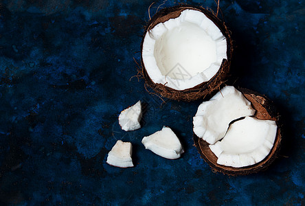 开阔椰子就躺在黑暗的蓝色背景上 旁边是破碎的碎片植物椰子药品食物牛奶水果异国情调外卖可可图片