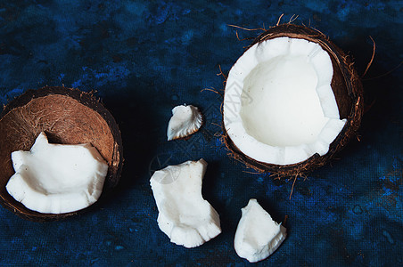 开阔椰子位于一片破碎碎片旁边的深蓝背景上水果牛奶异国食物药品坚果棕榈热带可可营养背景图片