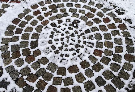 冬天旧鹅卵石路上的白雪表面材料街道历史性地面石头天气正方形路面城市卵石图片