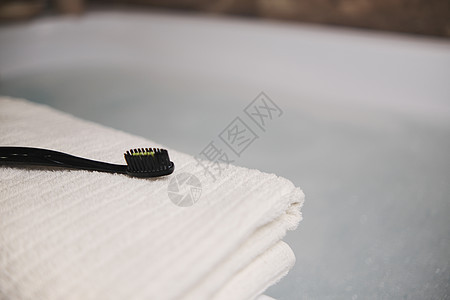 洗手间白毛巾上的黑色牙刷 底底色模糊的灰色蓝色树叶卫生玻璃海绵塑料女士牙科浴室竹子刷子图片