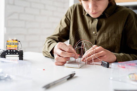 在科学项目实验板上与LED灯一起工作的男孩快乐闲暇孩子工程玩具班级青少年男生实验游戏图片