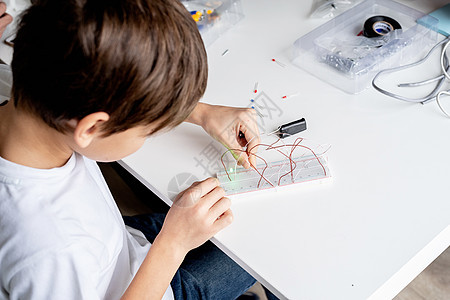 在科学项目实验板上与LED灯一起工作的男孩玩具游戏机器人快乐孩子青少年班级乐趣木板作坊图片