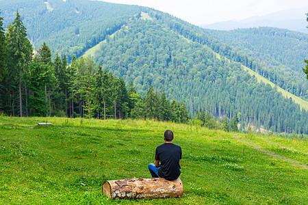 坐在原木上并享受和平的绿色山地景色的人 思想平静和放松闲暇高度森林远足者岩石男性远足运动石头旅游图片