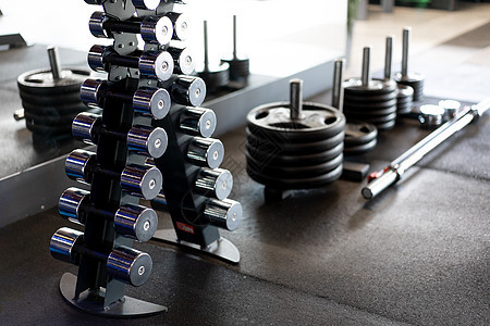在深灰色体育馆排成一排的哑铃肌肉健身房金属锻炼重量架子运动训练生活方式酒吧图片