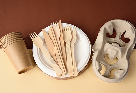 纸杯和木叉 用棕色背景的回收材料制成的空圆形棕色可支配板浪费包装野餐空白食物牛皮纸生态纸板圆圈家庭背景图片