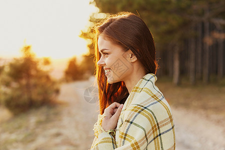 快乐的女士微笑 看在路边和树边 在背景中图片