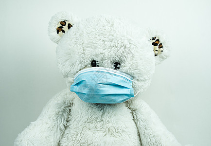白色背景的蒙面泰迪熊玩具褶皱外科样本防御棉签玩具熊疾病蓝色棉布背景图片