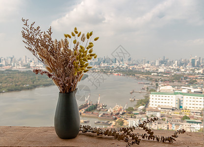 陶瓷花瓶中的干花在河景阳台的木桌上手工制作旅行花束热情陶器叶子天空制品景观植物家居图片