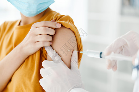 医生将疫苗注射到身戴医疗面具的病人肩部侧面 并用图片