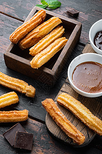 典型的西班牙零食churros 炸面糕饼通常配巧克力焦糖热辣酱 在旧黑木桌背景上烹饪油炸食物早餐面团棕色面包美食饼干油条图片