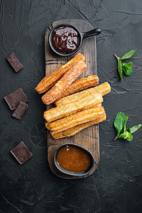 典型的西班牙零食churros 炸面糕饼通常配巧克力焦糖热辣酱 黑色背景 顶楼图片