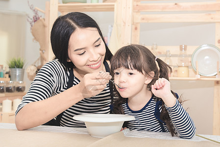 早上给可爱女儿吃健康早餐的亚洲母亲幸福家庭 笑声 她很可爱的女儿微笑乐趣童年厨师父母女孩牛奶享受教育厨房图片