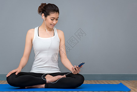 年轻的亚洲女性在瑜伽健康运动健身房练习瑜伽之前享受音乐 瑜伽和冥想对健康有好处 瑜伽运动和健康生活方式的照片概念运动服身体闲暇训图片