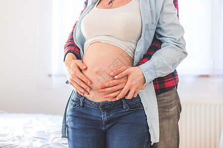 幸福的妈妈和爸爸抱着肚子怀孕 紧闭孩子们成人母亲胎儿父母拥抱身份后代母性投标图片