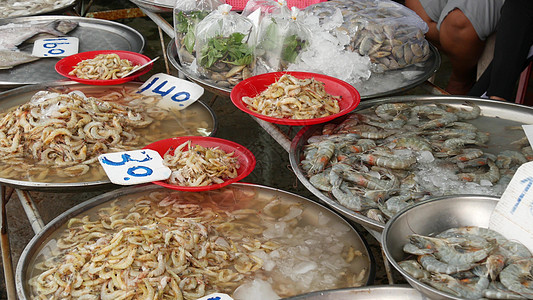 当地市场出售的海产品 从上面的新鲜香海鲜冰与市场货架上的价格 盛有水和价格标签的盆中的螃蟹 鱿鱼 虾和生龙虾食物销售营养产品店铺图片