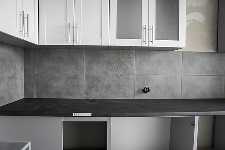 带有白色家具外墙 mdf 的定制厨柜安装 灰色模块化厨房由刨花板材料制成 处于不同的安装阶段 框架家具正面是 mdf 型材改造风图片