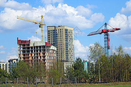 建筑起重机和建造现代房屋的景象与白云笼罩的蓝色天空相对图片