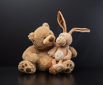 棕褐色泰迪熊膝上抱着一只玩具兔子图片