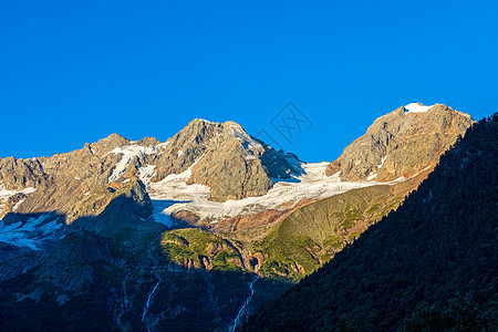 积雪高山和岩石的风景生态高地太阳爬坡阳光山脉旅游天空日落森林图片