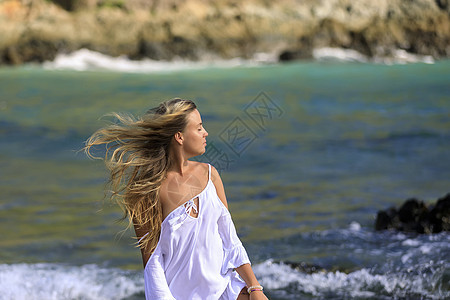 海边美丽的年轻女孩 头发长着的美发假期冒充太阳卷发脖子帽衫金发女郎女士海滩裙子图片