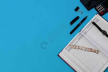 带有空白笔记本 笔和用品的现代办公桌工作场所 复制蓝背景的空间 顶视图 平面风格 字母周三图片