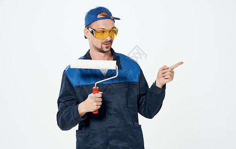 男子修补彩漆蓝蓝色西装和帽子眼镜滚筒房间工具装潢男人建设者装修画家承包商刷子图片