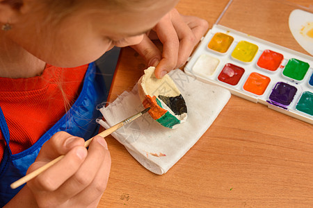 女孩用水彩色画着盐面纸的手工艺品图片