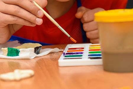 女孩在从盐面纸上画一幅手工艺品时 用所想要的颜色刷油漆图片