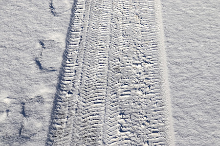 近距离观察积雪覆盖的街道上的轮胎痕迹季节摄影胎迹车轮牵引力小路旅行雪堆天气冒险图片