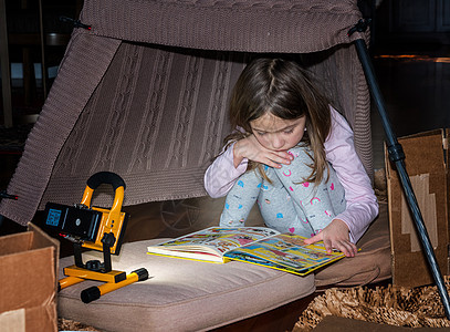 女童在自制帐篷里玩耍和阅读漫画书;女孩图片