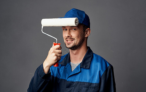 一个修黄色眼镜的男子 和墙壁涂漆的滚滚机工人滚筒男人男性帽子装潢装潢师承包商工作职业图片