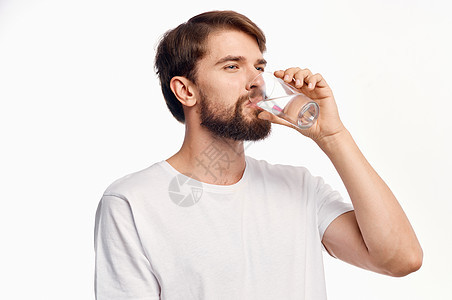 从玻璃杯中喝水的英俊男子 看上去很惊异 看起来情绪化饮食饮料液体白色口渴生活工作室玻璃营养矿物图片