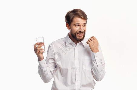 快乐的人喝水 从玻璃杯的水 在光背景白衬衫肖像模型上工作室生活男人营养矿物手指男性玻璃饮食口渴图片