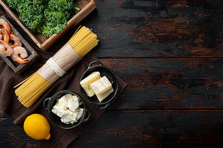 海鲜意大利面的配料 虾 意大利面 帕尔马干酪 乳清干酪 在旧的深色木桌背景上 顶视图平躺 有复制空间和文本空间图片