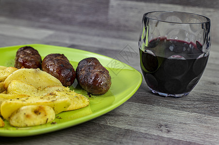 土豆香肠和一杯葡萄酒猪肉小吃盘子迷迭香美食蔬菜玻璃餐厅香肠桌子图片