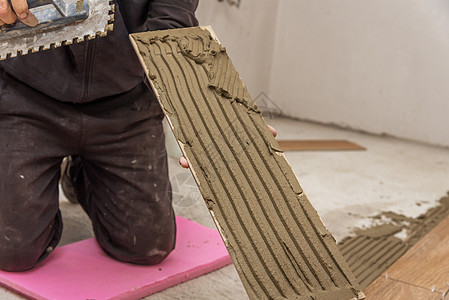 工人把陶瓷地板砖放在粘合表面工具材料地面风格制品大理石水泥装饰工作推杆图片