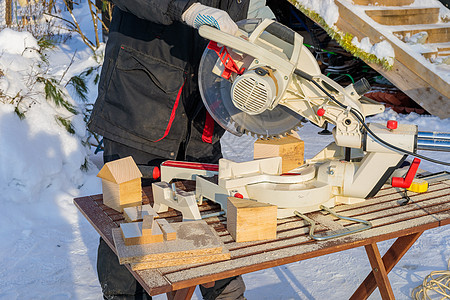 一名男性工人用电锯和盘子切开一个街区建筑工人木匠木制品体力劳动者工作技术手套职业工具精神图片