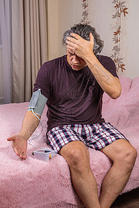 一位50岁的男子用一吨的计数器测量他的血压脉冲疾病高血压心脏病学微笑诊断沙发仪表老年检查背景图片